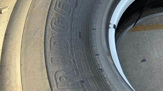 Close-up of large stacked tires with a white rim, dusty ground visible nearby.