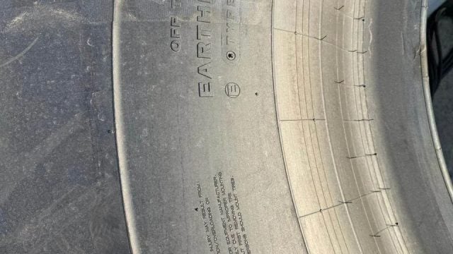 Close-up of a tire sidewall showing the brand name 'EARTHMOTION' and warning text, with tread visible along the edge.