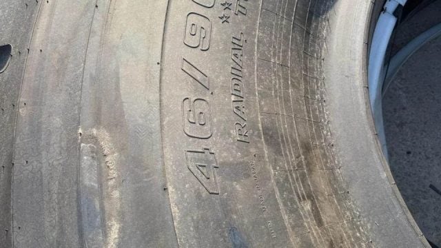 Close-up of a large, worn tire showing its rugged tread and sidewall markings.