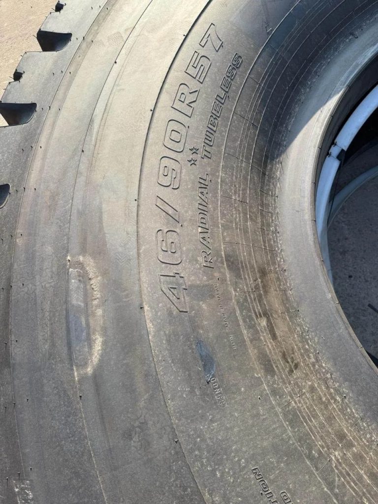 Close-up of a large, worn tire showing its rugged tread and sidewall markings.