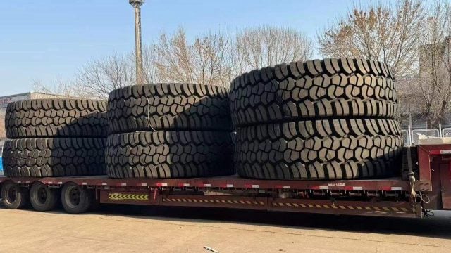 Large stack of heavy-duty tires on a flatbed trailer ready for transport.